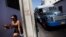 Una joven camina cerca de un camión de transporte de pasajeros en la ciudad de Santiago de Cuba.